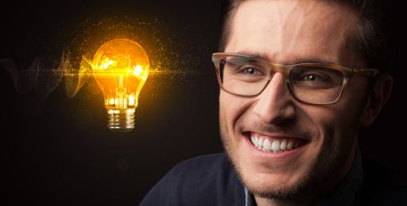 Portrait of a young businessman with a lightbulb next to him on a dark background