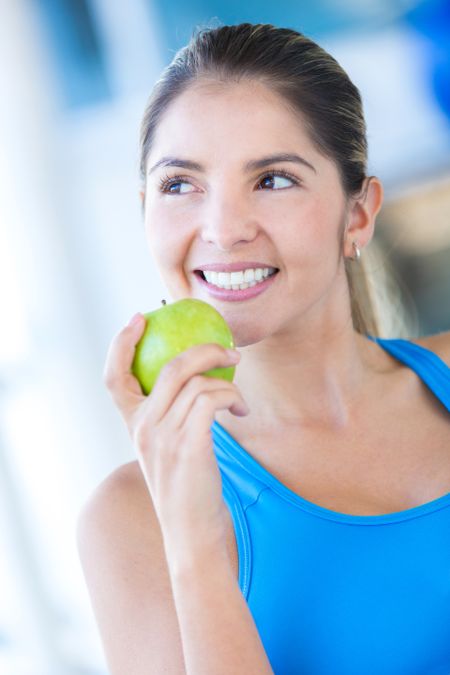 Healthy woman eating an apple at the gym