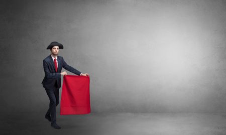Businessman standing with red toreador cloth in his hand in an empty room