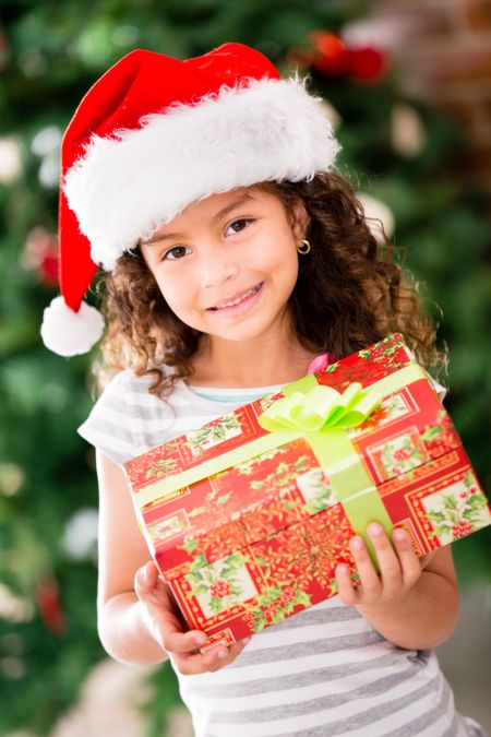 Christmas girl wearing a Santa hat and holding a present