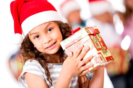 Adorable girl holding Christmas present and wearing Santa's hat