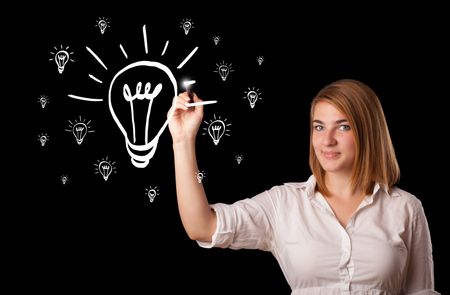 Young woman drawing light bulb on whiteboard