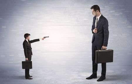 Tiny businessman with gun shooting giant fearful businessman