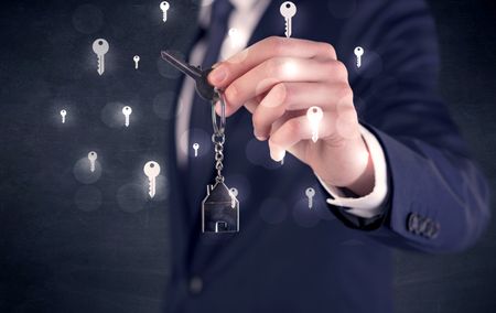 Businessman in suit holding keys with keys graphics around and dark background
