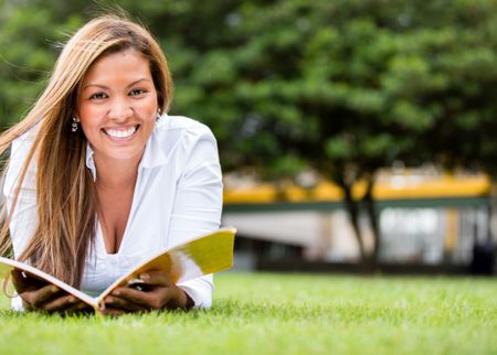 Female student lying at the park reading a book