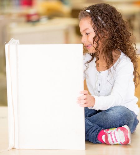 Little girl reading a book at the library