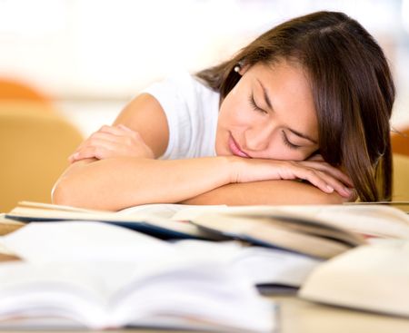 Tired female student at the library falling asleep