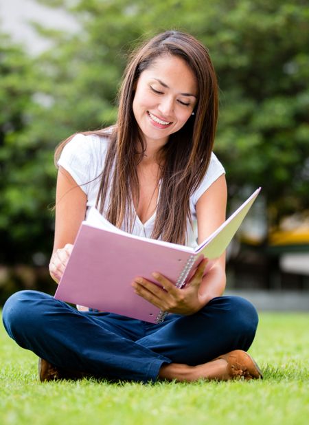 Woman studying outdoors with an open notebooks