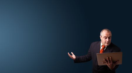 businessman in suit holding a laptop and presenting copy space