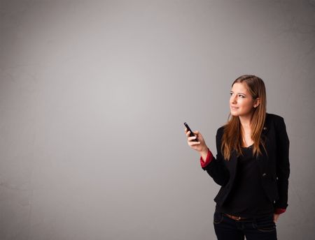 attractive young lady standing and holding a phone with copy space