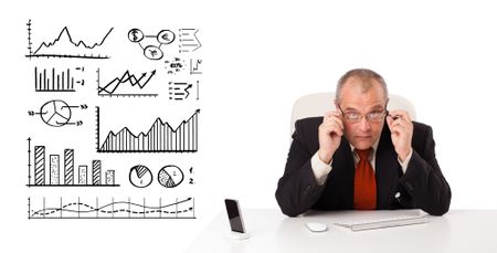 Businessman sitting at desk with diagrams and graphs, isolated on white