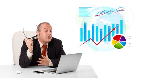 Businessman sitting at desk with laptop and statistics, isolated on white