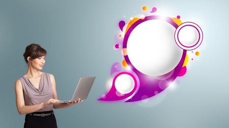 attractive young woman holding a laptop and presenting abstract speech bubble copy space