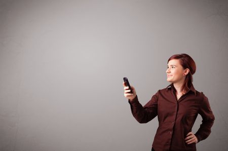 attractive young lady standing and holding a phone with copy space