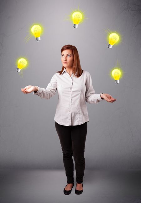 beautiful young lady standing and juggling with light bulbs