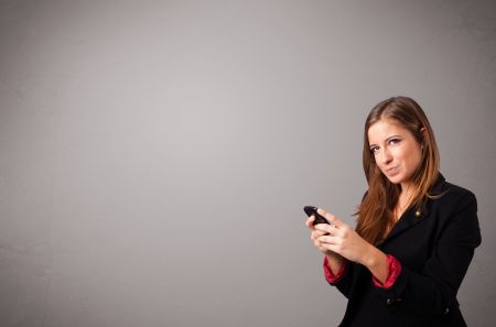 attractive young lady standing and holding a phone with copy space