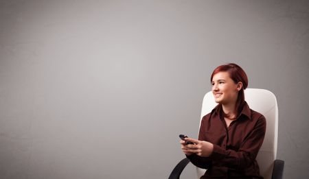 attractive young lady sitting and holding a phone with copy space