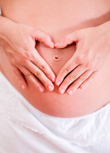 Loving mother making a heart on her pregnant belly