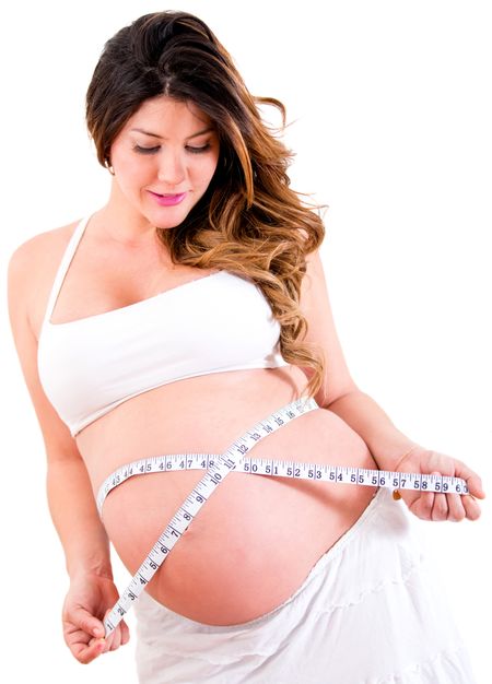 Pregnant woman measuring her belly - isolated over a white background