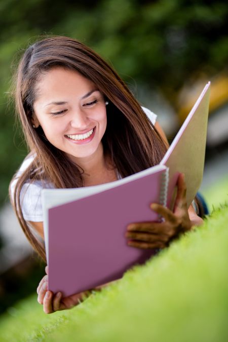 Female student studying outdoors looking very happy
