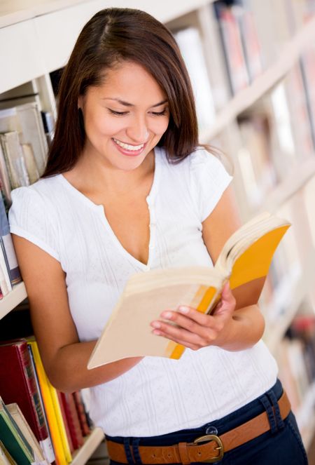 Female student reading a book at the library