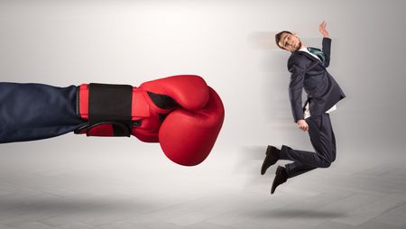 Giant hand gives a kick to a small employee businessman