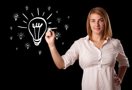 Young woman drawing light bulb on whiteboard