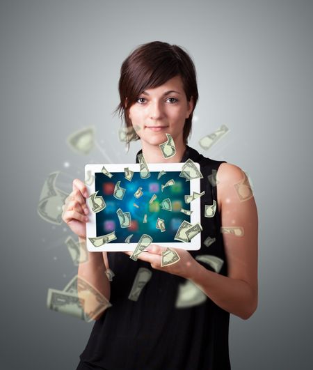 beautiful young woman holding tablet with money