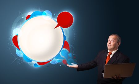 Businessman in suit holding a laptop and presenting abstract modern speech bubble with copy space