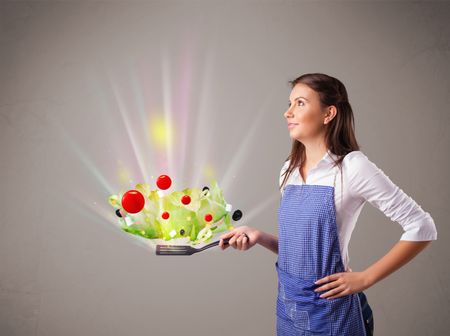 Beautiful young woman cooking fresh vegetables with abstract lights