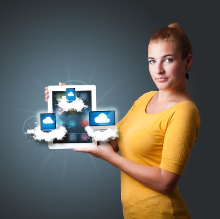 Beautiful young woman holding tablet with modern devices in clouds