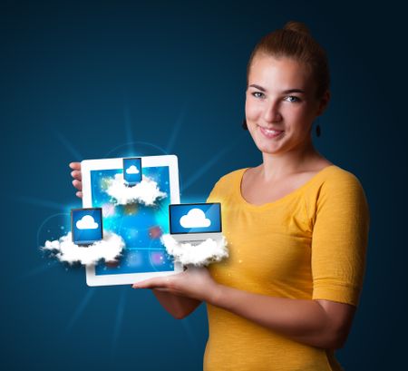 Beautiful young woman holding tablet with modern devices in clouds