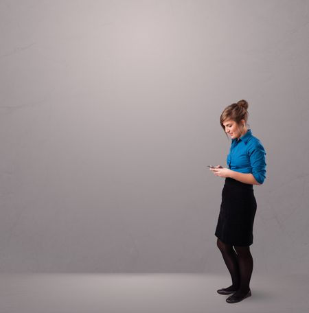 attractive young lady standing and holding a phone with copy space