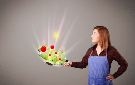 Beautiful young woman cooking fresh vegetables with abstract lights