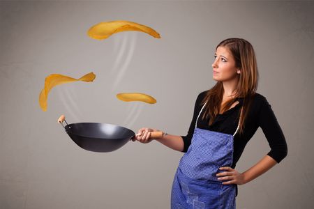 Beautiful young woman making pancakes