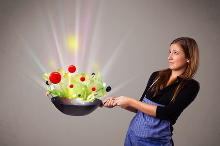 Beautiful young woman cooking fresh vegetables with abstract lights