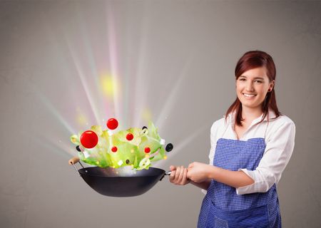 Beautiful young woman cooking fresh vegetables with abstract lights