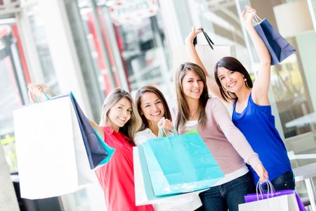 Happy group of shopping women with arms up