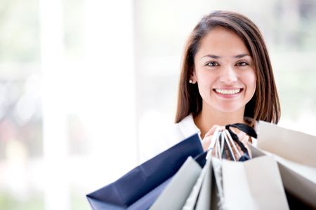 Latin woman holding shopping bags looking happy