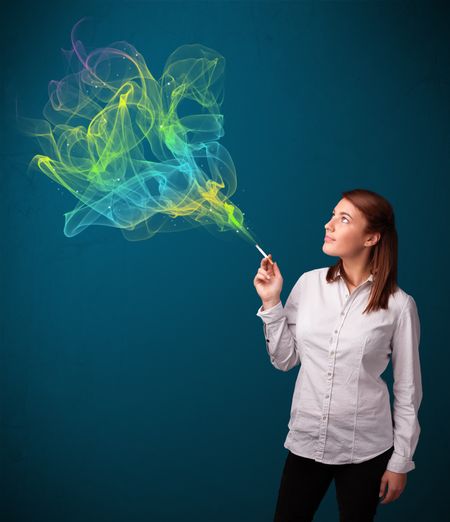 Pretty young lady smoking cigarette with colorful smoke