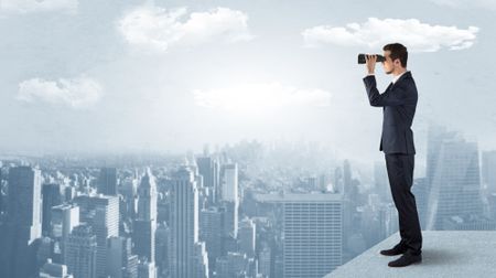 Businessman looking forward to a city  with binoculars from skyscraper concept