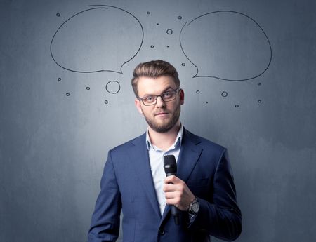 Businessman speaking into microphone with speech bubbles over his head