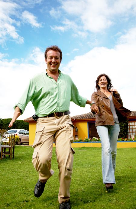 happy couple running outdoors outside their home having fun