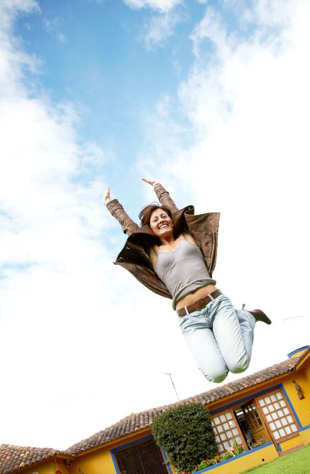 happy woman jumping and smiling outside her home