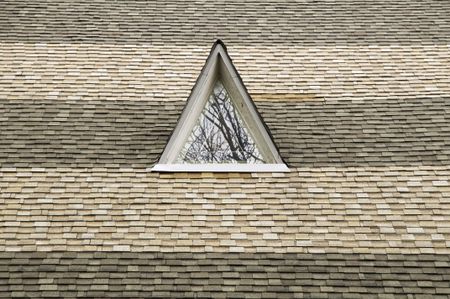Triangular window on roof of Protestant church with alternating bands of shingles