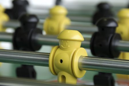 Smiling face of plastic yellow player on foosball rod. In the U.S. and Canada, table football is usually called foosball.