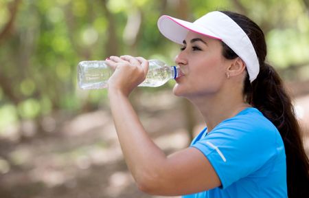 Sportive woman drinking water after her workout