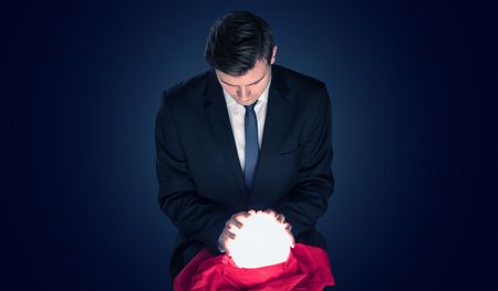 Handsome businessman with magic ball and copy space and dark background