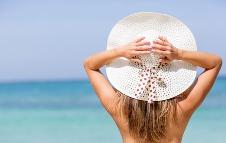 Beautiful woman at the beach wearing a hat