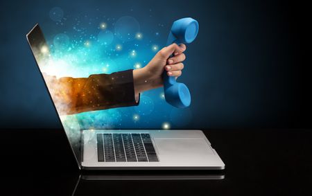 Hand with phone coming out of a laptop with sparkling effects